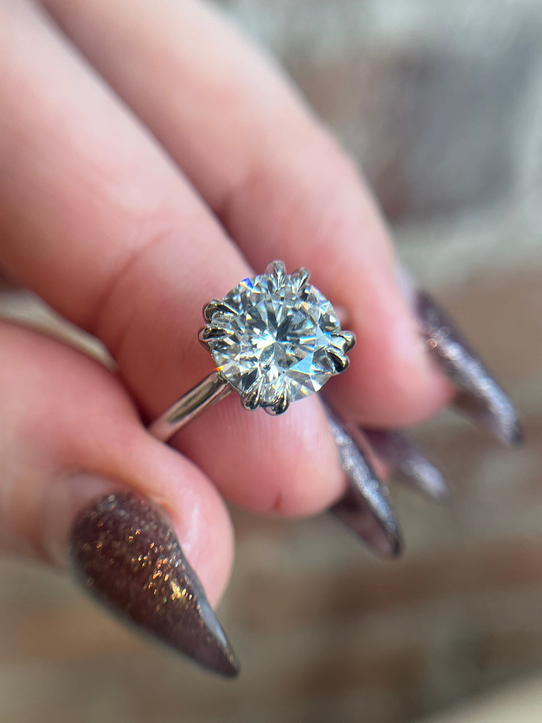 Diamond ring held between fingers with a blurred background
