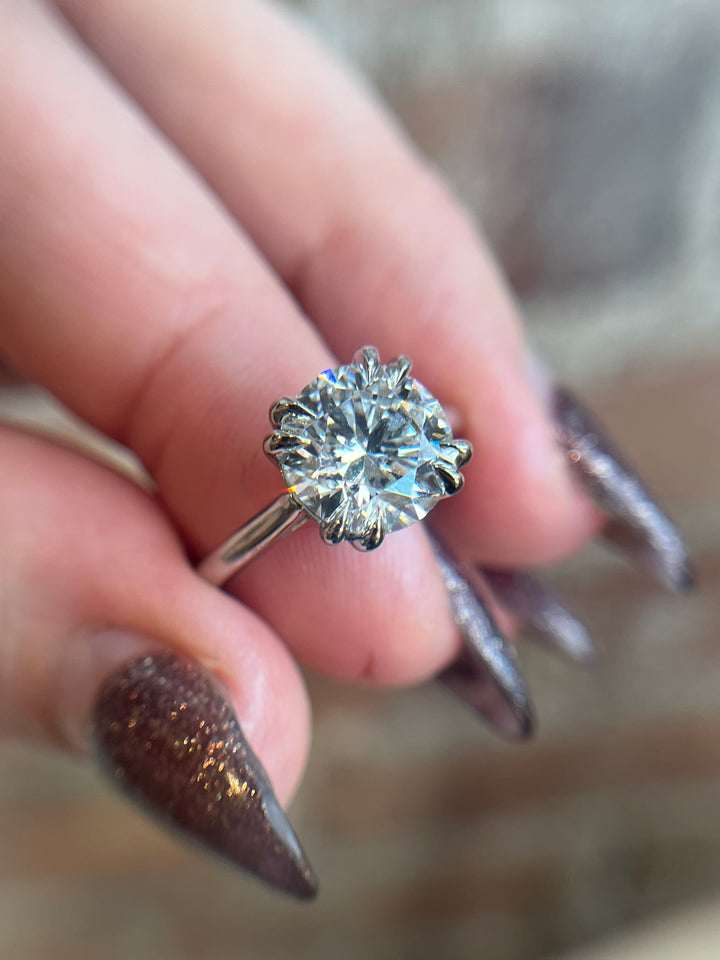 Diamond ring held between fingers with a blurred background
