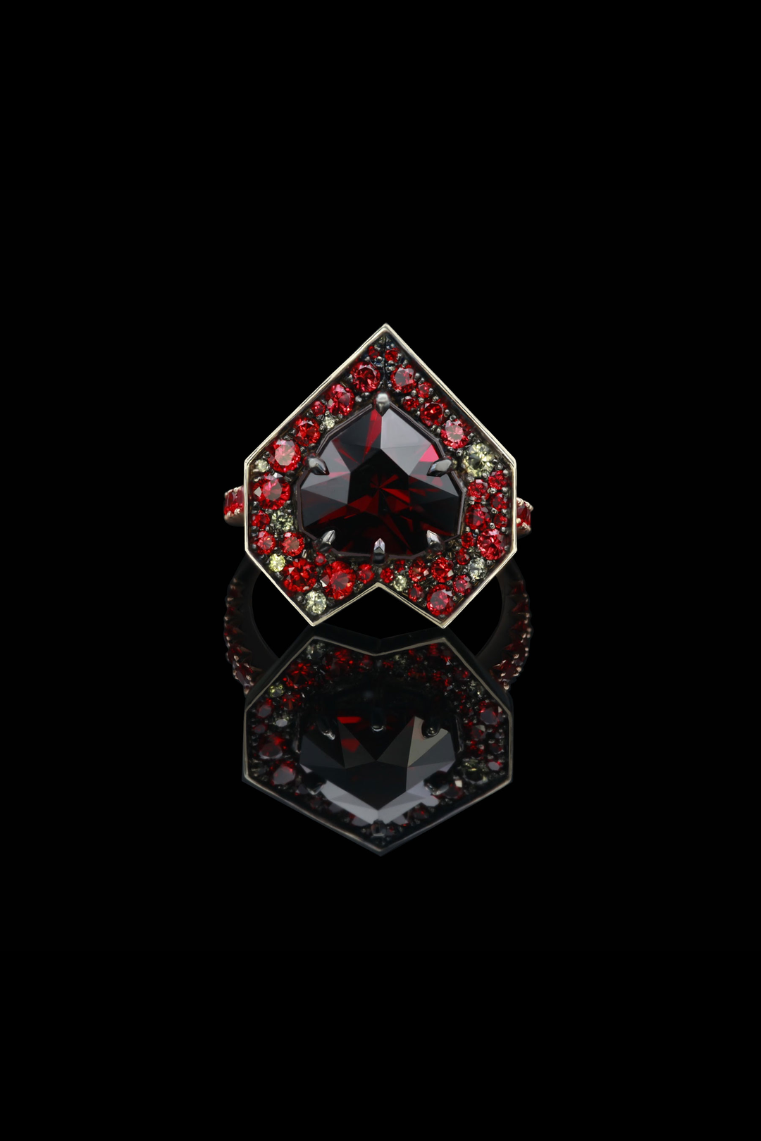 Front Facing image of custom designed Ring with hear-shaped, fancy cut garnet and random pave set sapphires around. The top of the ring is an angular heart shape. Stones are mostly red in colour.