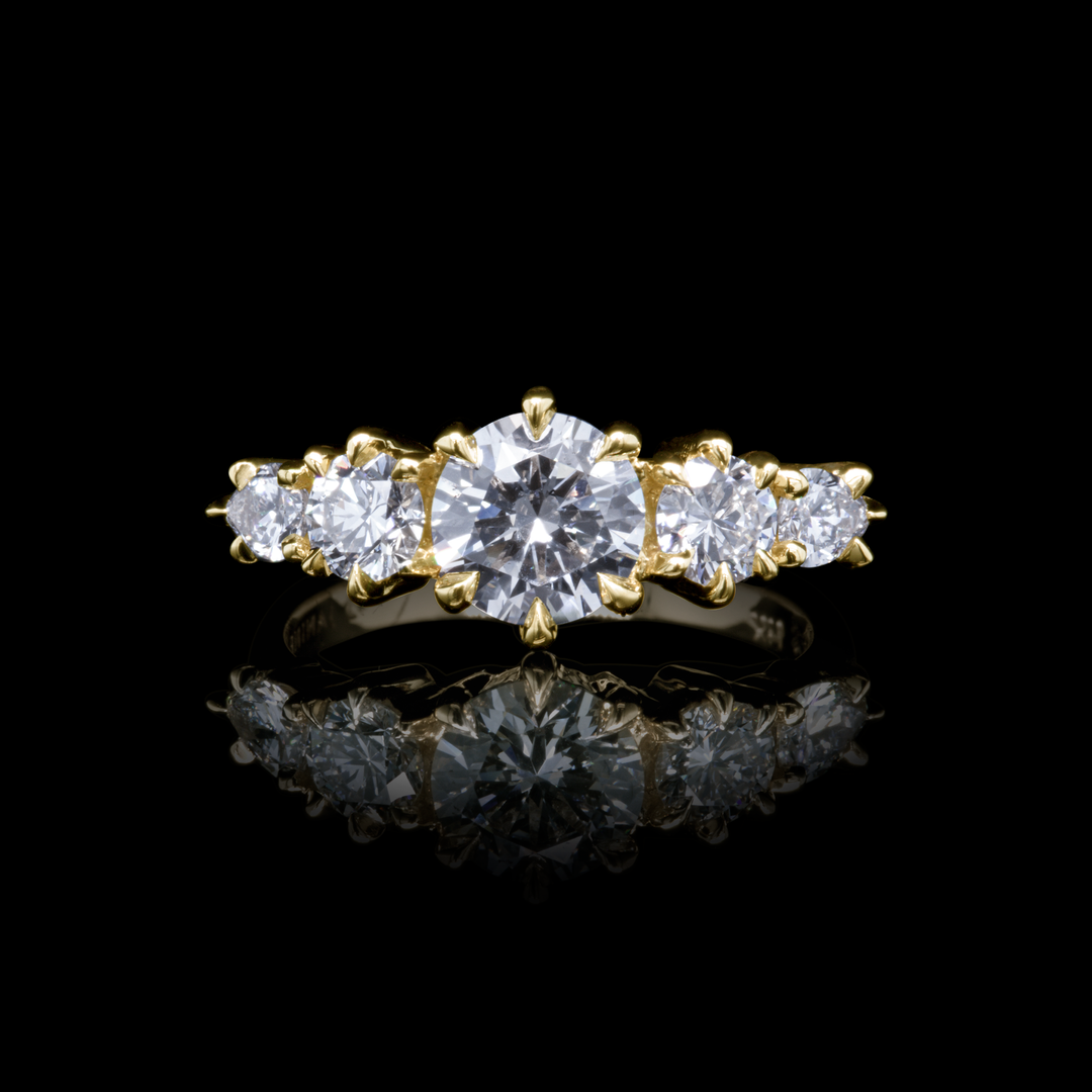 Aurea Ring laying flat to highlight its polished 18K gold band and sparkling diamond center stone