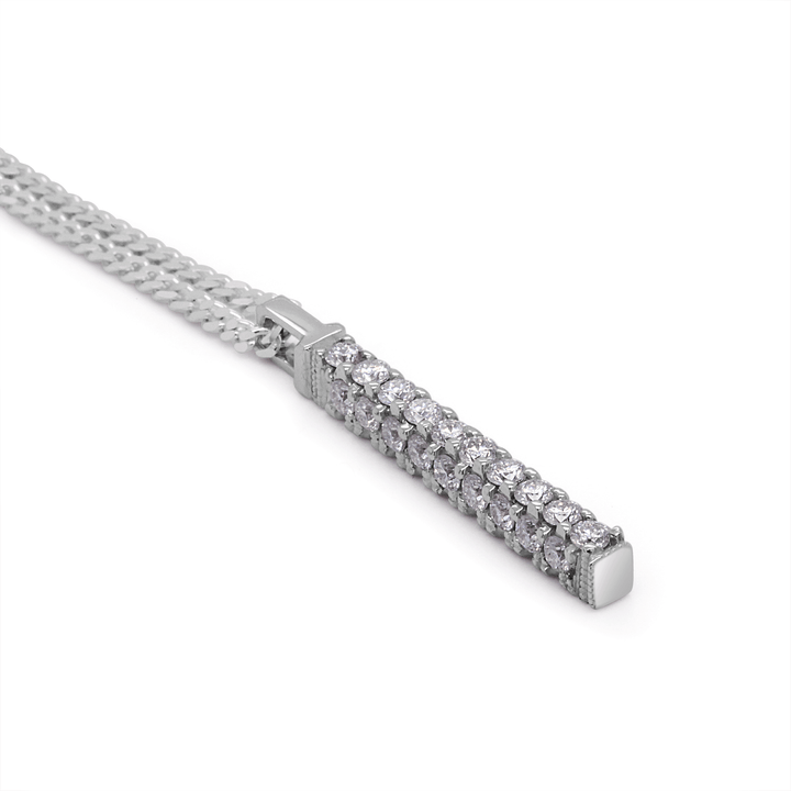 Twenty-eight round moissanite stones pave-set in a three-sided platinum bar pendant, suspended on a sleek flat silver Cuban link chain. (White background). Laying flat  on white surface.