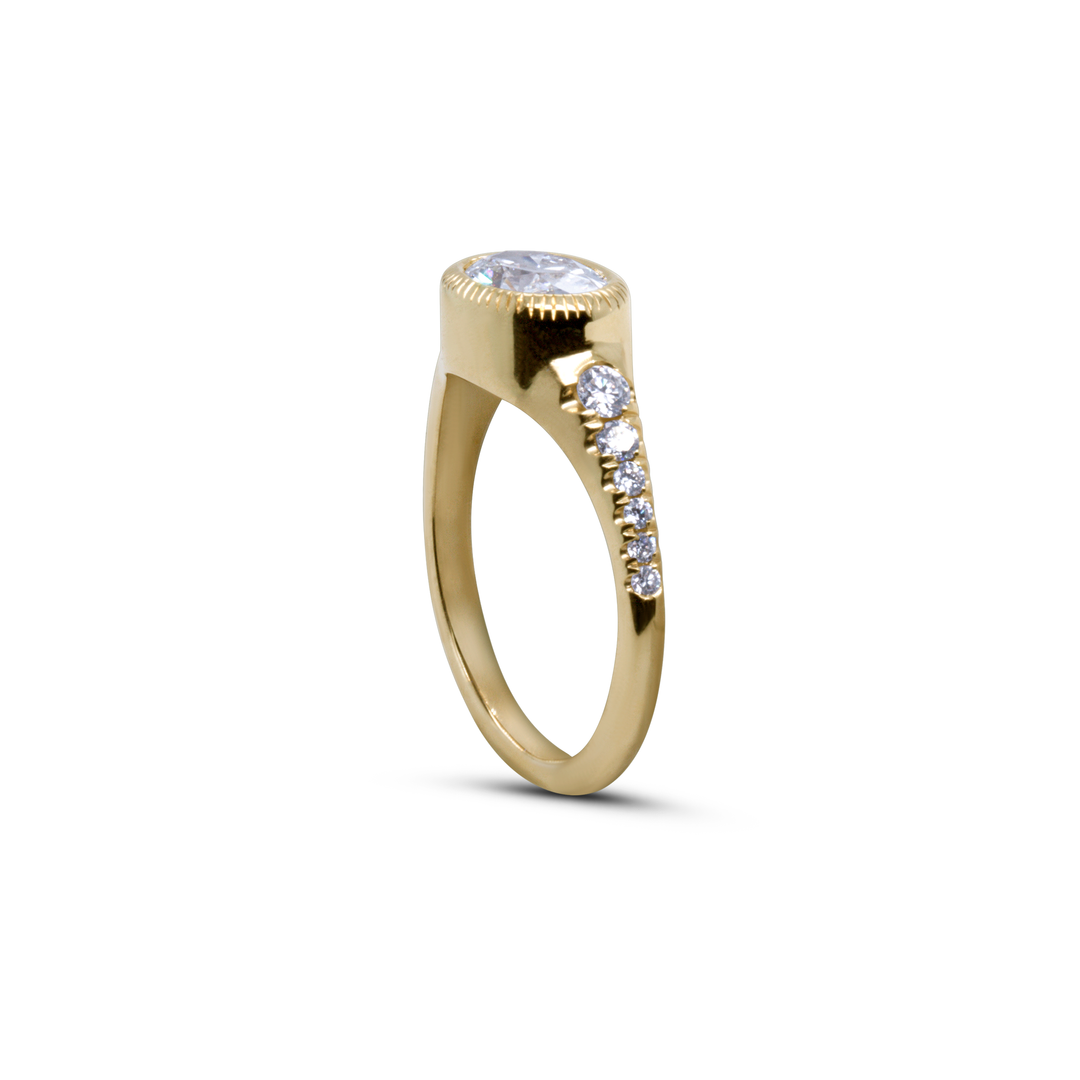Profile of oval diamond engagement ring in yellow gold, featuring raised solitaire setting and pavé band.
