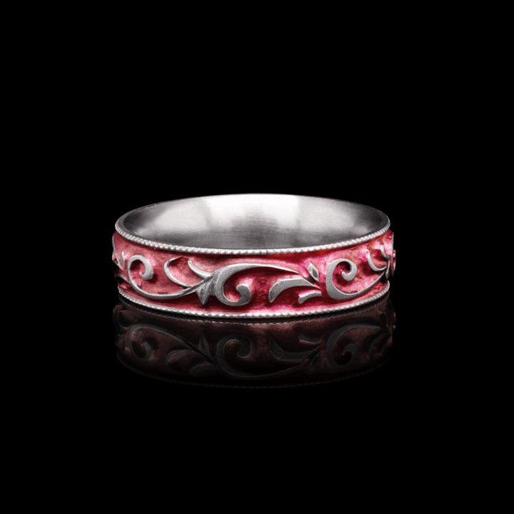 Side view of Botanical Blush titanium ring in anodized pink, showing intricate hand-engraved vine scrollwork, displayed on a black background.