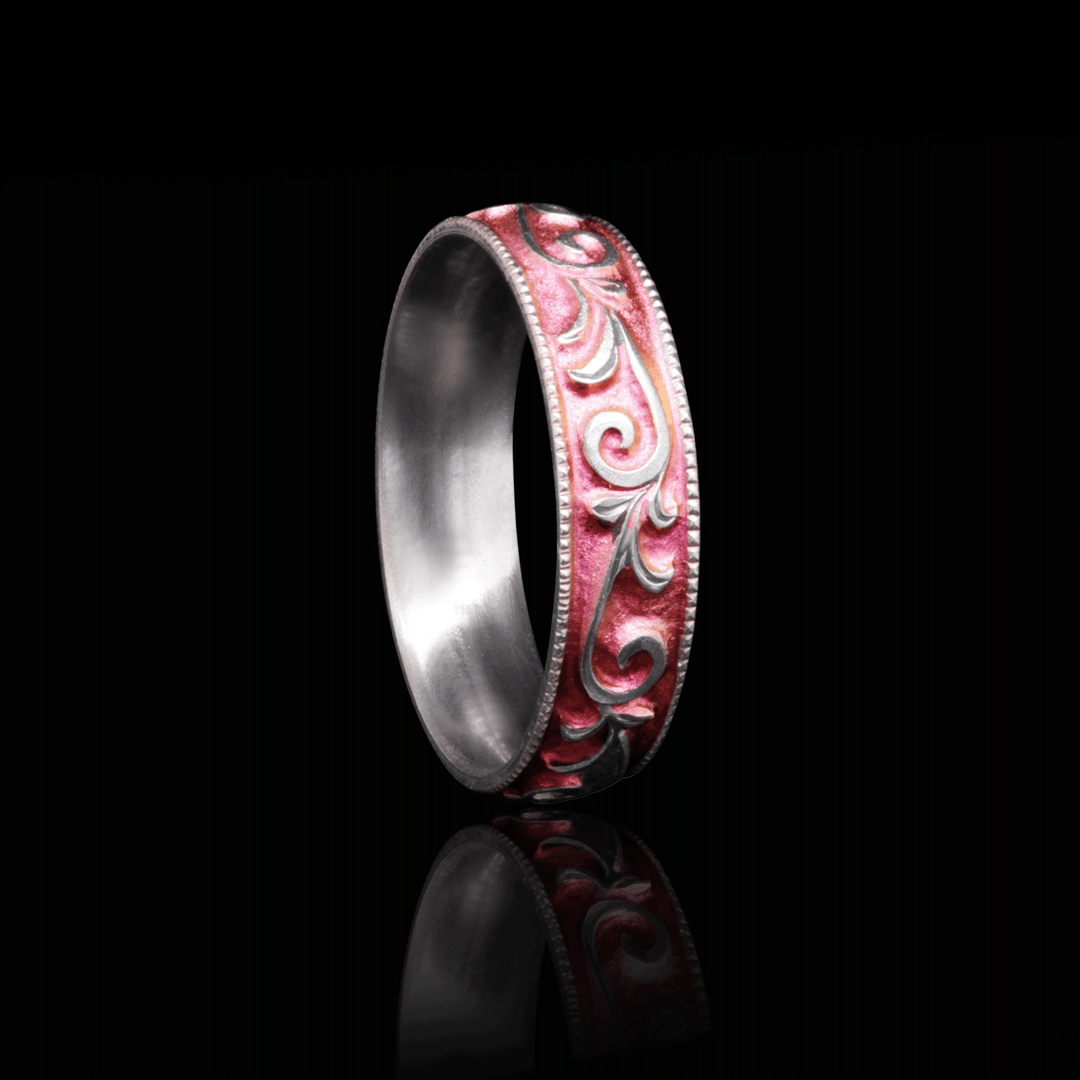 Angled view of titanium ring with pink anodized finish and detailed vine engraving, showcased against a black background for a striking effect.