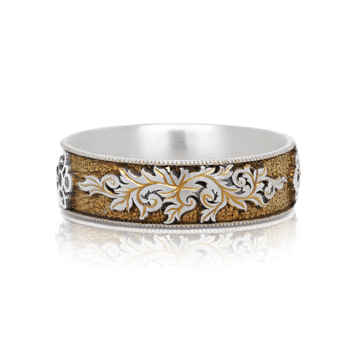 Close-up of Gilded Gate titanium ring, featuring  scroll designs and gold anodization. Displayed on a white background.