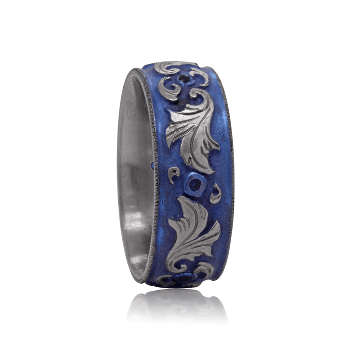 View of Lagoon Lustre titanium ring, featuring blue anodized finish, vine-inspired engraving, and sapphire accents, set on a white background.