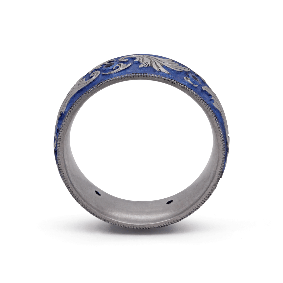 Through finger view of blue anodized titanium ring with six bezel-set blue sapphires and intricate scroll design, displayed on a white background.