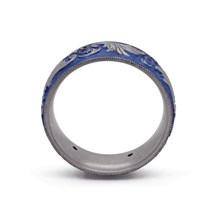 Through finger view of blue anodized titanium ring with six bezel-set blue sapphires and intricate scroll design, displayed on a white background.
