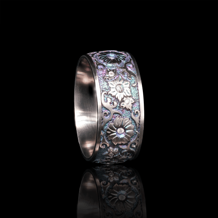 Side view of Floral Fantasy ring in titanium, showcasing floral engravings with white moissanite stones set in bezel, against a black background.