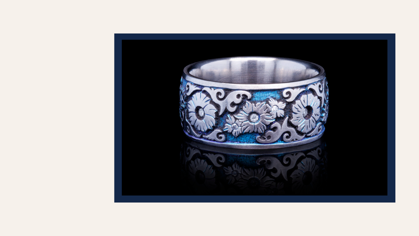 Handcrafted Titanium ring with floral engraving and vibrant blue accents, reflecting artistic craftsmanship and attention to detail.
