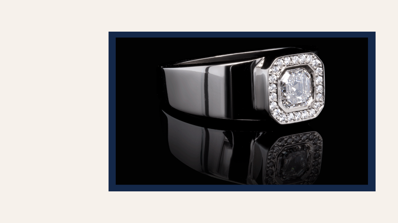 A sleek 18K white gold ring featuring an asscher-cut diamond center stone surrounded by a halo of sparkling pavé diamonds. The ring is elegantly displayed against a reflective black background, emphasizing its modern and luxurious design.