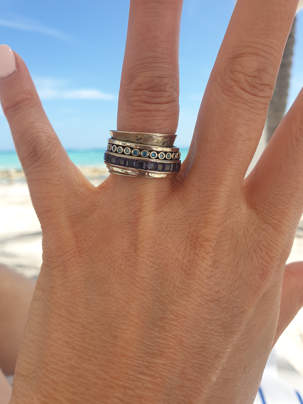 client wearing 18K white gold spinning ring with diamonds and sapphires