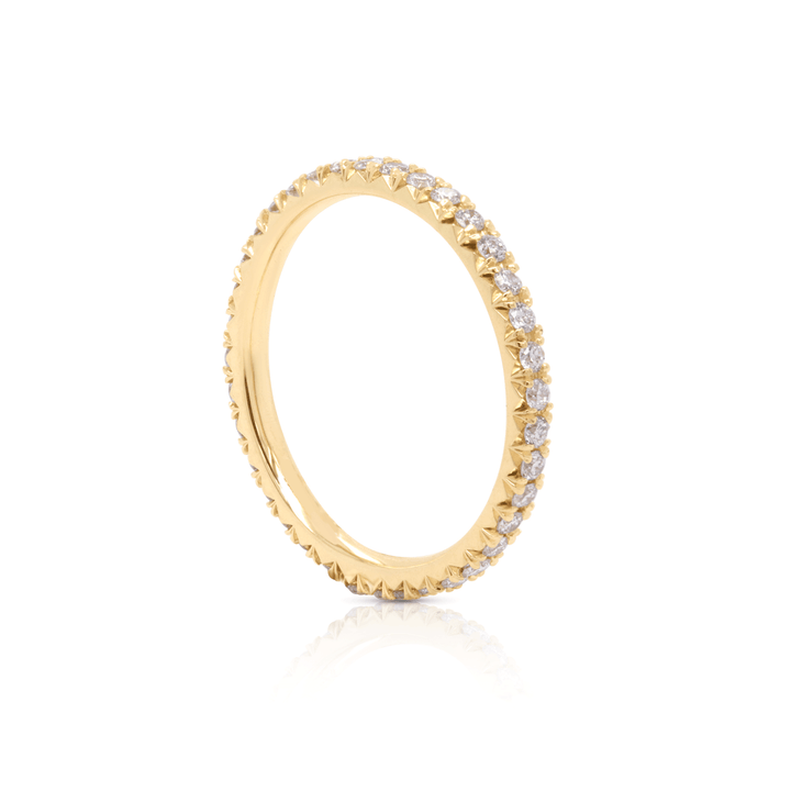 Stackable diamond eternity ring in 18K yellow gold, featuring a unique and captivating comet tail design. 3 quarter view of ring on white background.