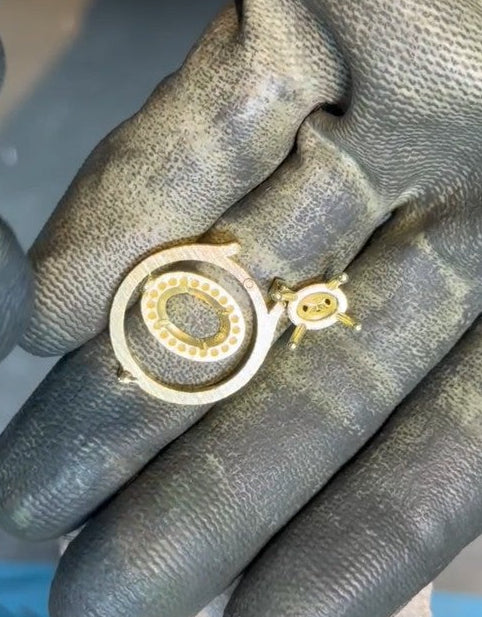 A gold ring casting on a gloved hand