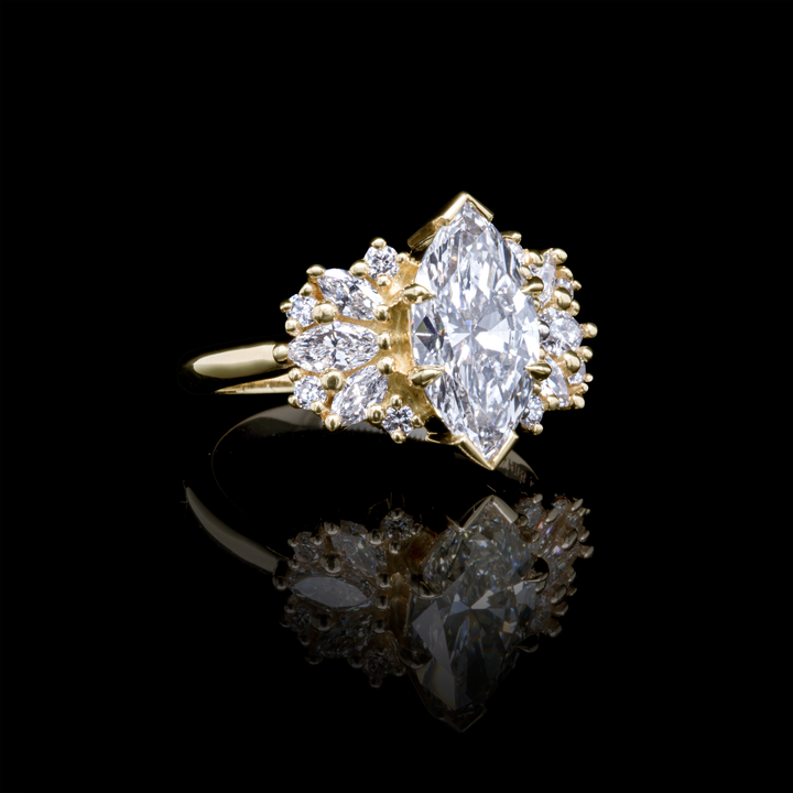 Marquise diamond Clara engagement ring in yellow gold, organic diamond frame design, reflective black background.