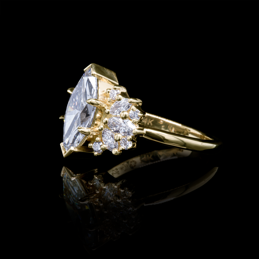 Clara 2ct marquise lab diamond ring in recycled yellow gold with accent diamonds, side perspective on black background.