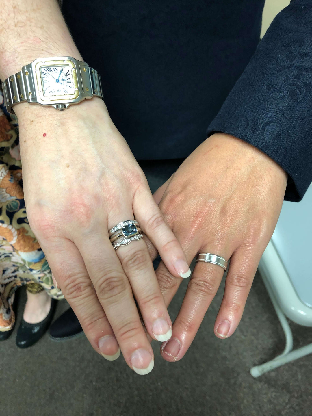 A couple showing off their hands with their brand new custom designed engagement ring and wedding bands