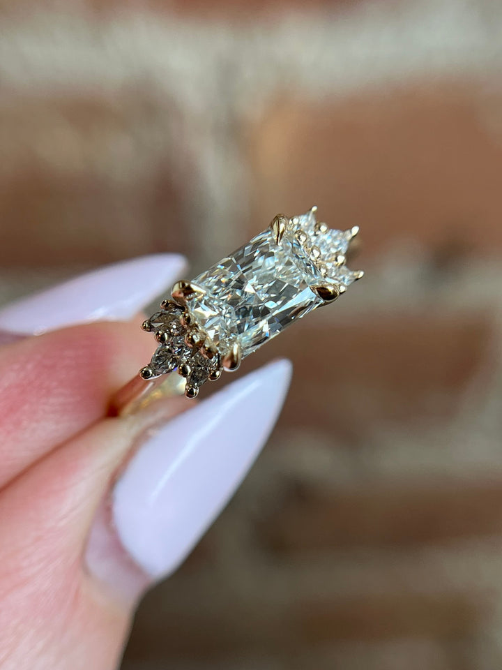 Radiant cut lab-grown diamond engagement ring in yellow gold, east-west detail view on model’s hand, Janine Jewels.