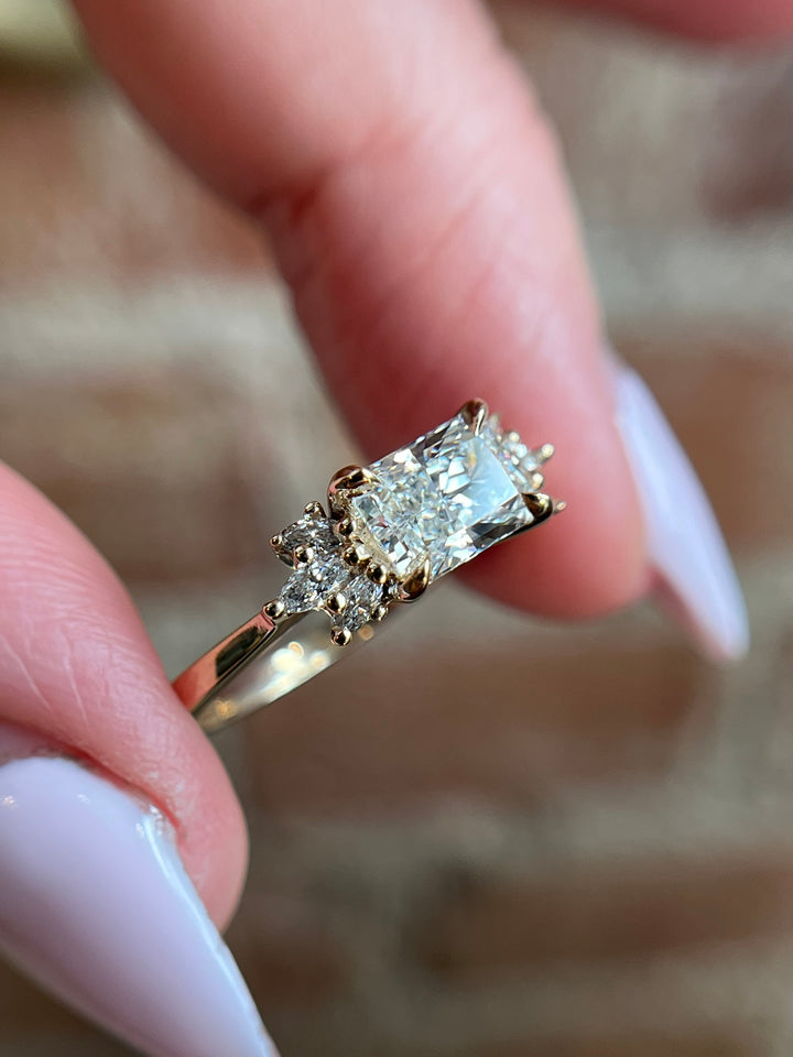 Radiant cut lab diamond engagement ring in yellow gold with marquise side stones, worn on hand, Janine Jewels Toronto.