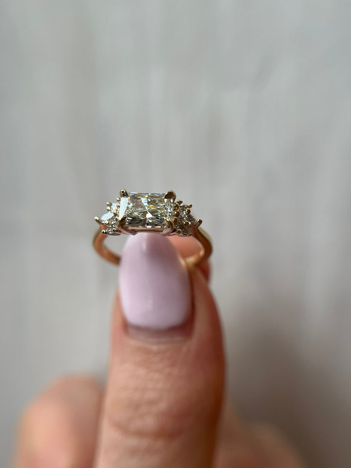 14K yellow gold radiant diamond engagement ring with accent stones, worn on hand in natural light, fine Toronto jeweller.