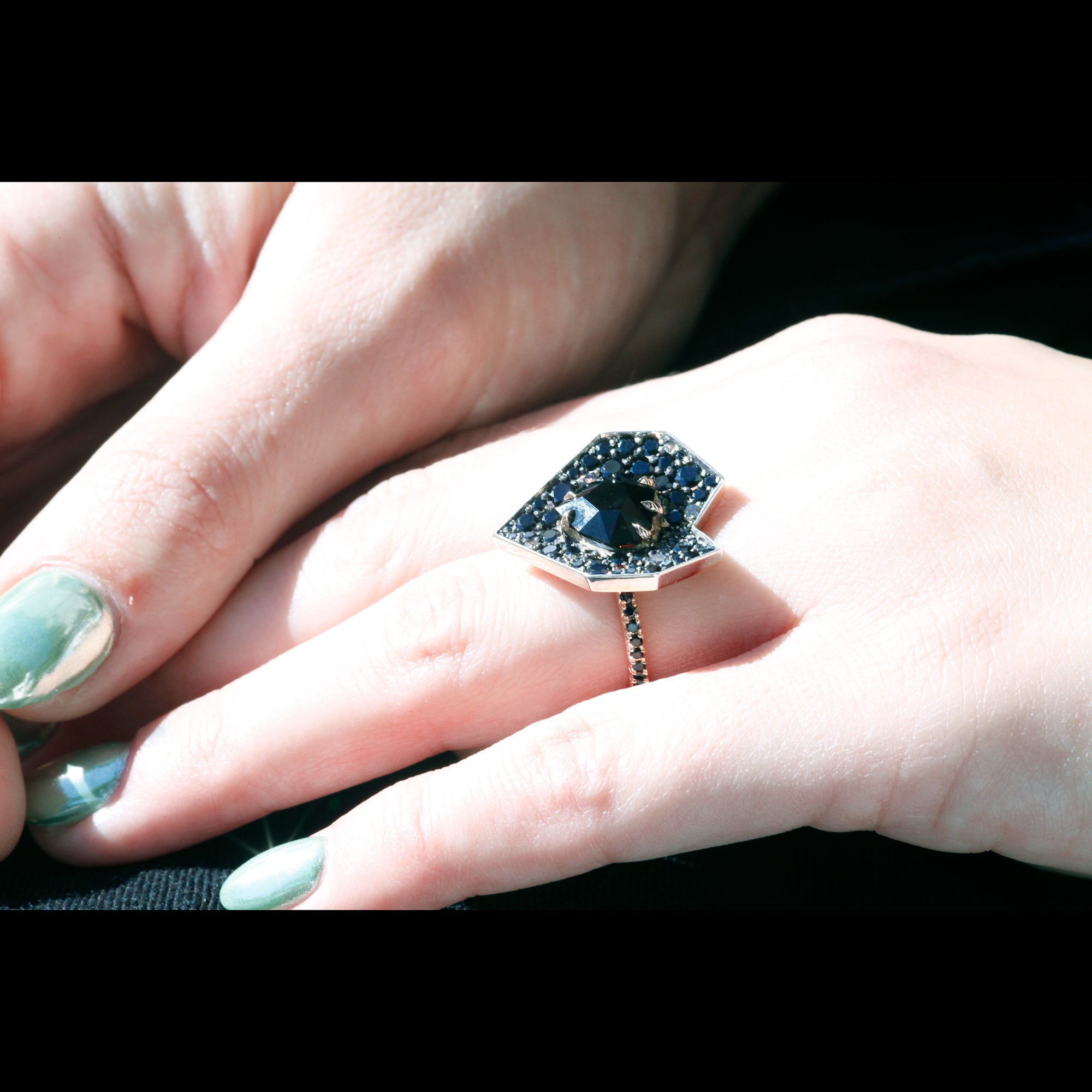 Heart-shaped statement ring on hand with pave set sapphires and spinel center stone