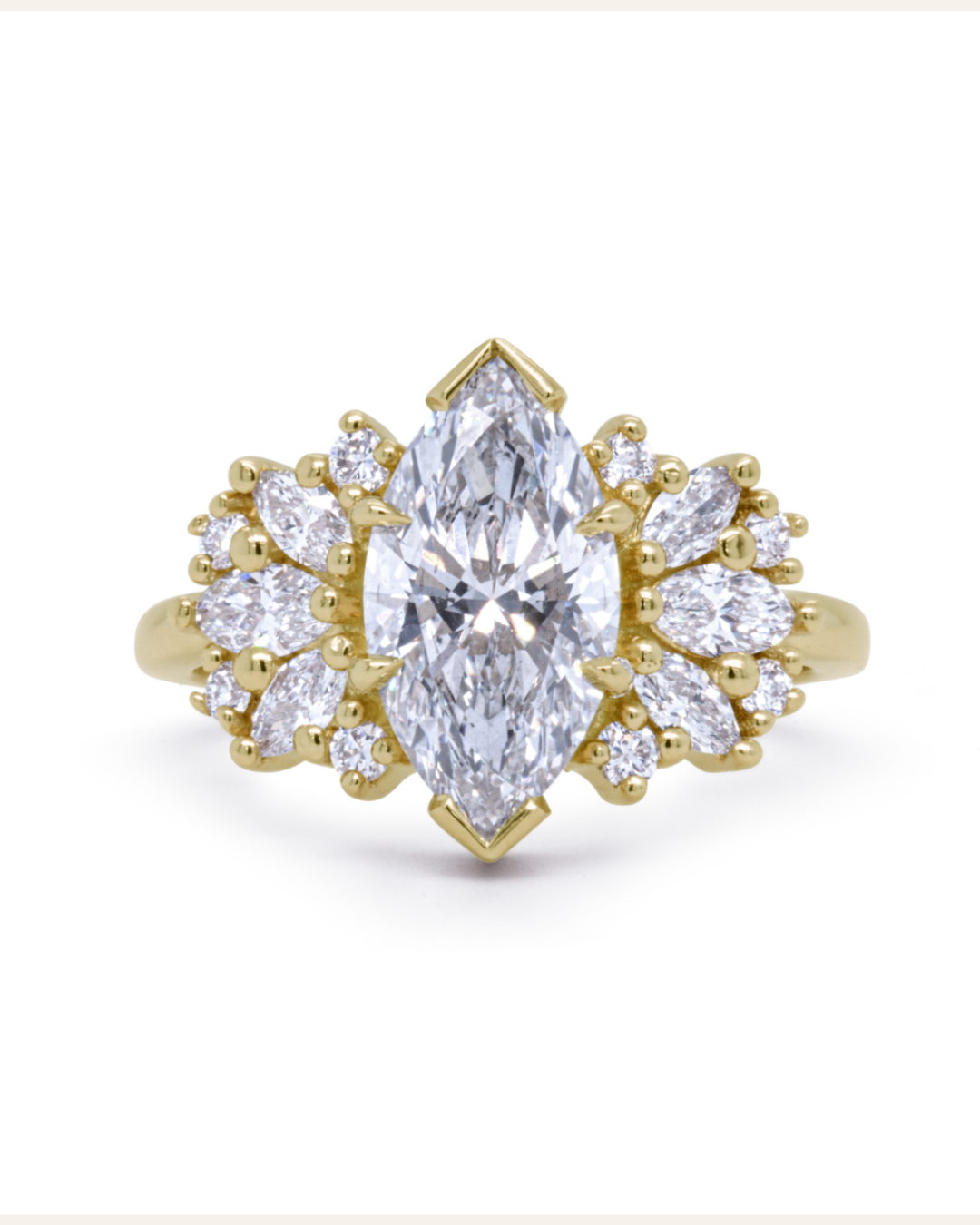Gold ring on white background with marquis center stone and marquis and round accent stones. All diamonds