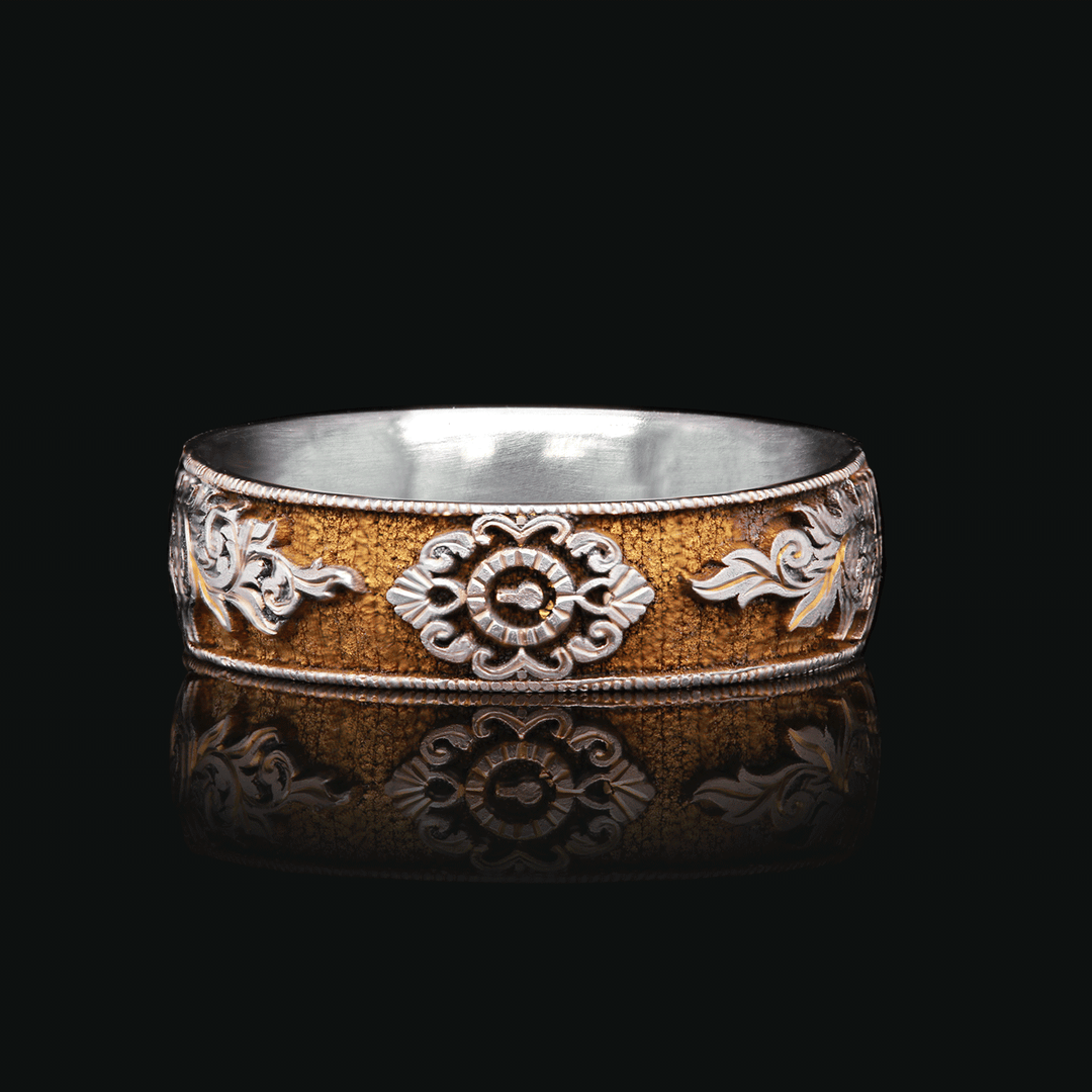 Close-up of Gilded Gate titanium ring with gold anodized finish and intricate vintage-inspired engravings of a lock and scrolls, set against a black background.