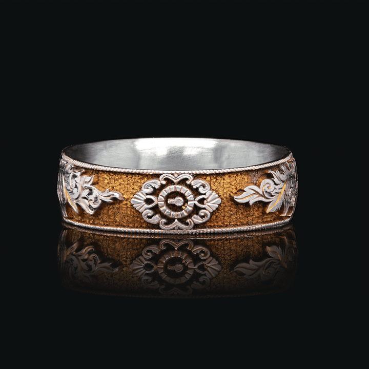Close-up of Gilded Gate titanium ring with gold anodized finish and intricate vintage-inspired engravings of a lock and scrolls, set against a black background.