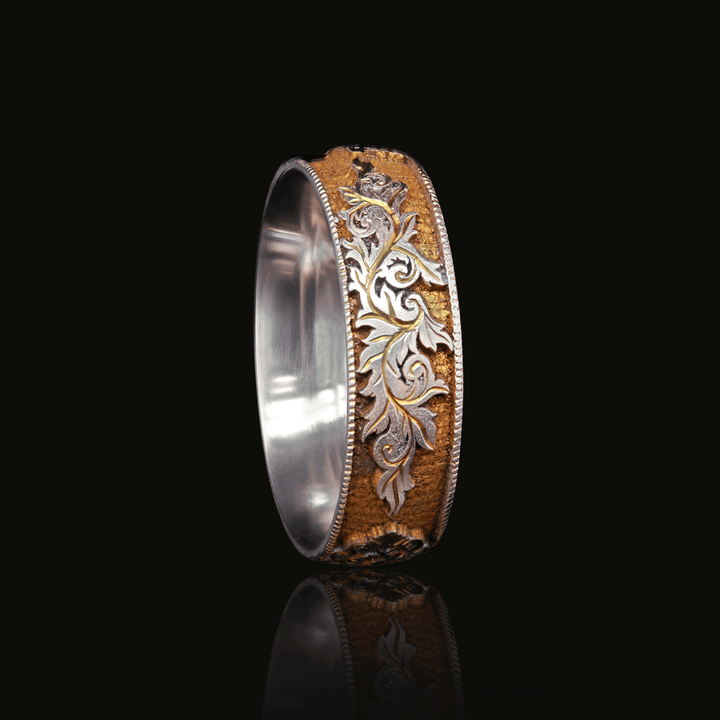 Three quarter view of Gilded Gate titanium ring with gold anodized finish and intricate vintage-inspired engravings of a lock, key and scroll, set against a black background.