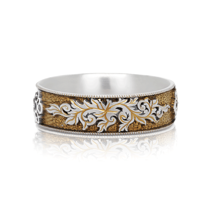 Close-up of Gilded Gate titanium ring, featuring  scroll designs and gold anodization. Displayed on a white background.