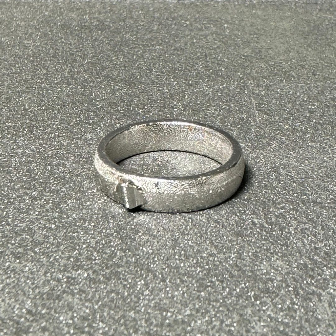 Close-up of a custom platinum wedding band with hand-engraved scrollwork and a classic polished finish.