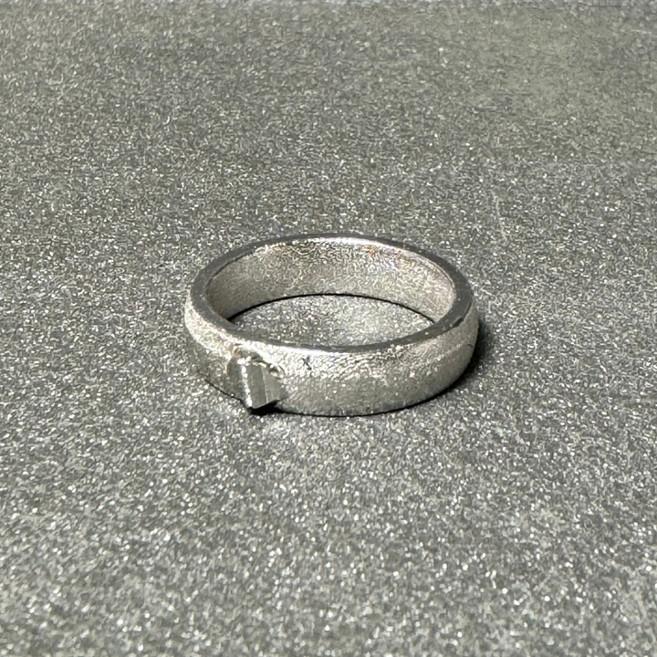 Close-up of a custom platinum wedding band with hand-engraved scrollwork and a classic polished finish.